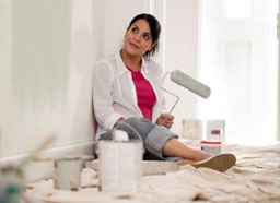 Woman taking a break from paiting a wall, smiling.